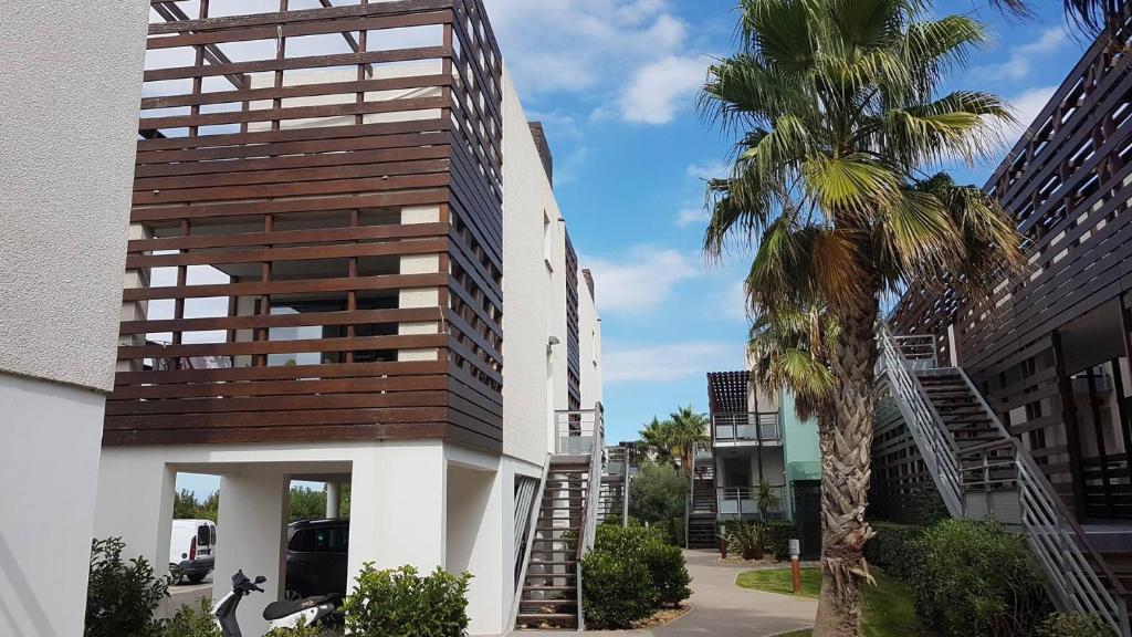 un edificio con una palma accanto a un edificio di Vacances au calme pour cette villa de standing proche du Golf - GOLFC10 a Saint-Cyprien-Plage
