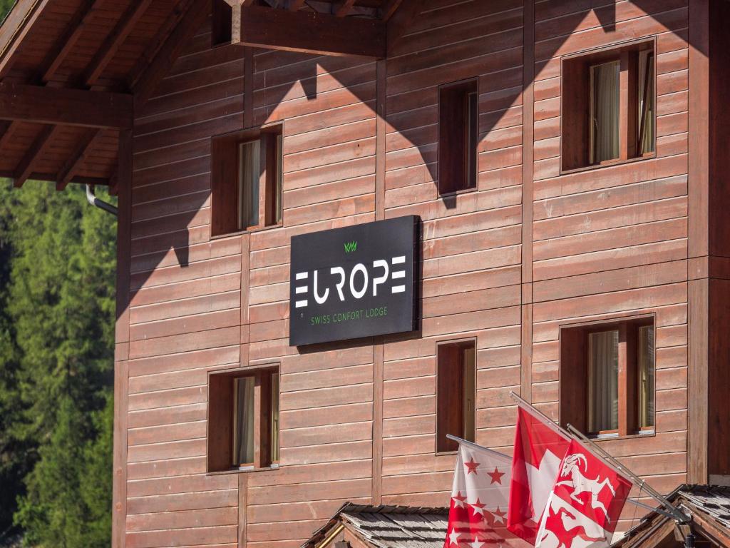 un panneau sur le côté d'un bâtiment avec drapeaux dans l'établissement Hotel Europe, à Zinal