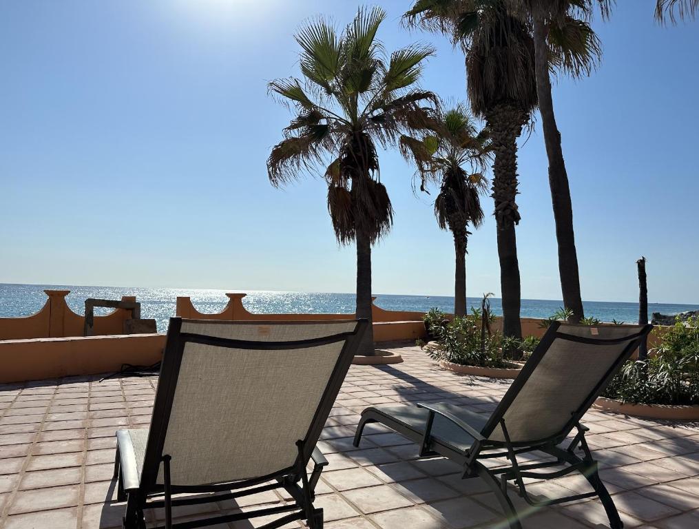 2 sedie su un patio con palme e l'oceano di Villa del Mar - Paradise in Cabo Pulmo! villa a Cabo Pulmo