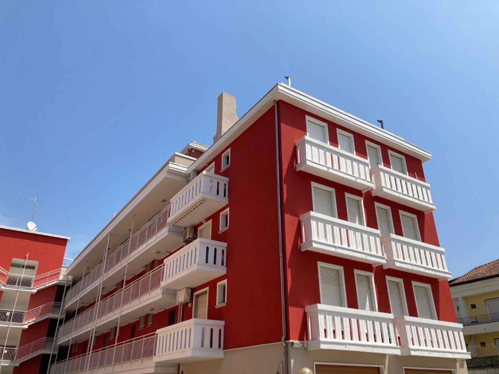ロザピネタにあるTwo-Bedroom Apartment in Rosolina Mare/Venetien 25064の白いバルコニー付きの赤い建物
