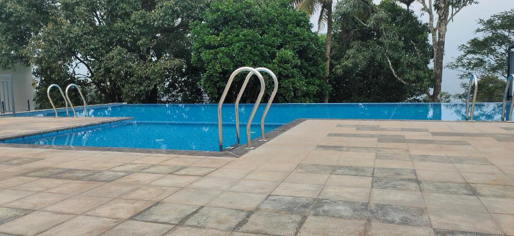 a swimming pool with two metal chairs next to it at Winter Note Resorts in Munnar
