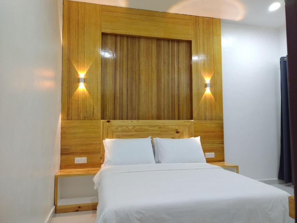 um quarto com uma cama branca e 2 almofadas em FUNDUQ AL BUSYRA em Pantai Cenang