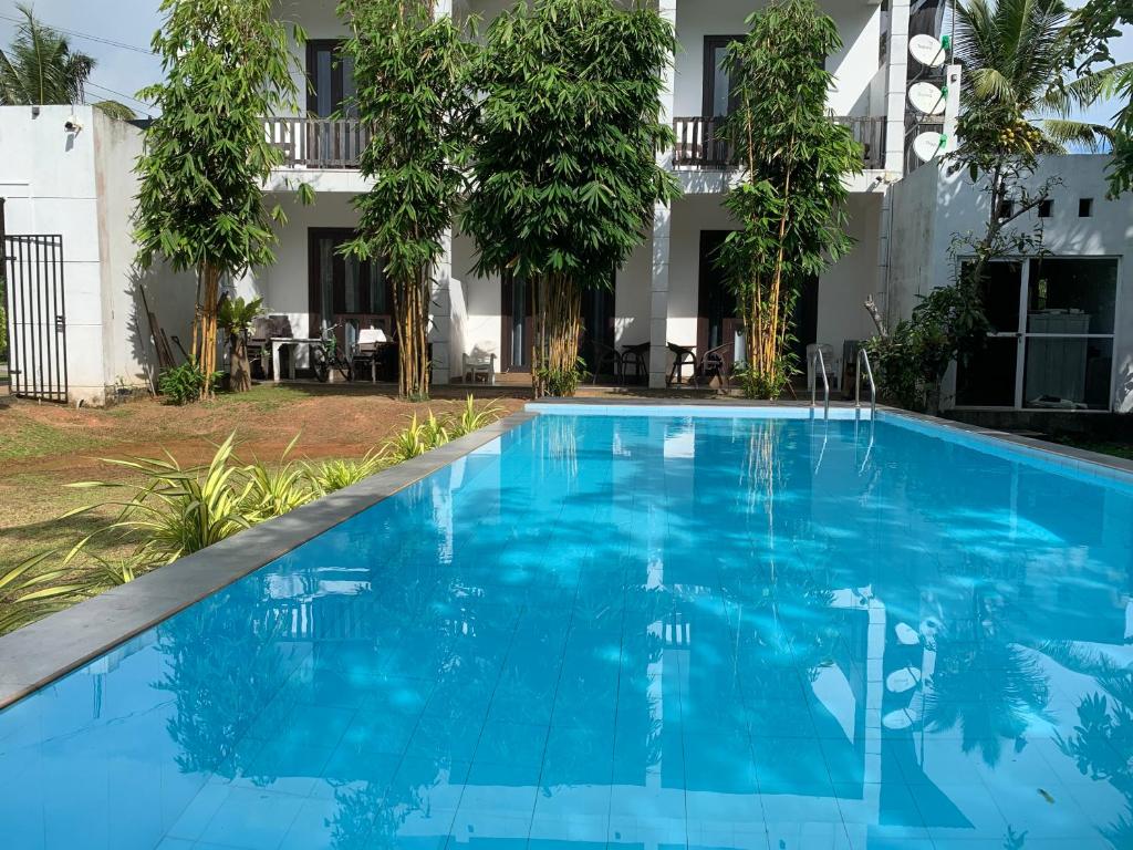 a blue swimming pool in front of a building at KITHULA Boutique Hotel in Hikkaduwa