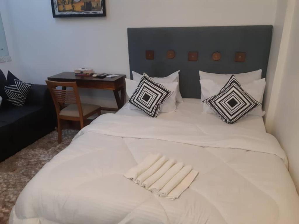 a large white bed with pillows and a table at Apartment with beautiful view, free wifi, swimming pool and gym in Dar es Salaam