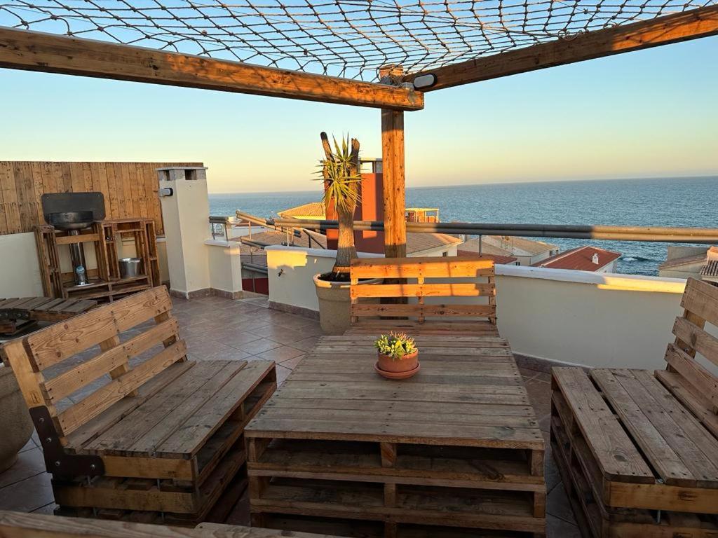 una terraza con bancos de madera y vistas al océano. en LA GEODA vivienda vacacional turística 8 personas en Villaricos
