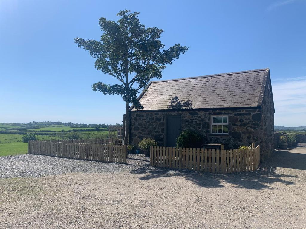 a stone barn with a fence and a tree at RB Contractor Stays - Celyn in Pwllheli