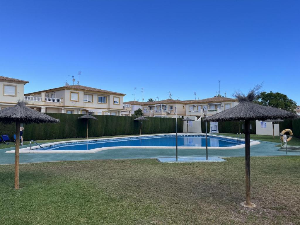 a swimming pool with umbrellas in a yard at Playa Flamenca 2 bed Apt Sol De Mar in Villamartin