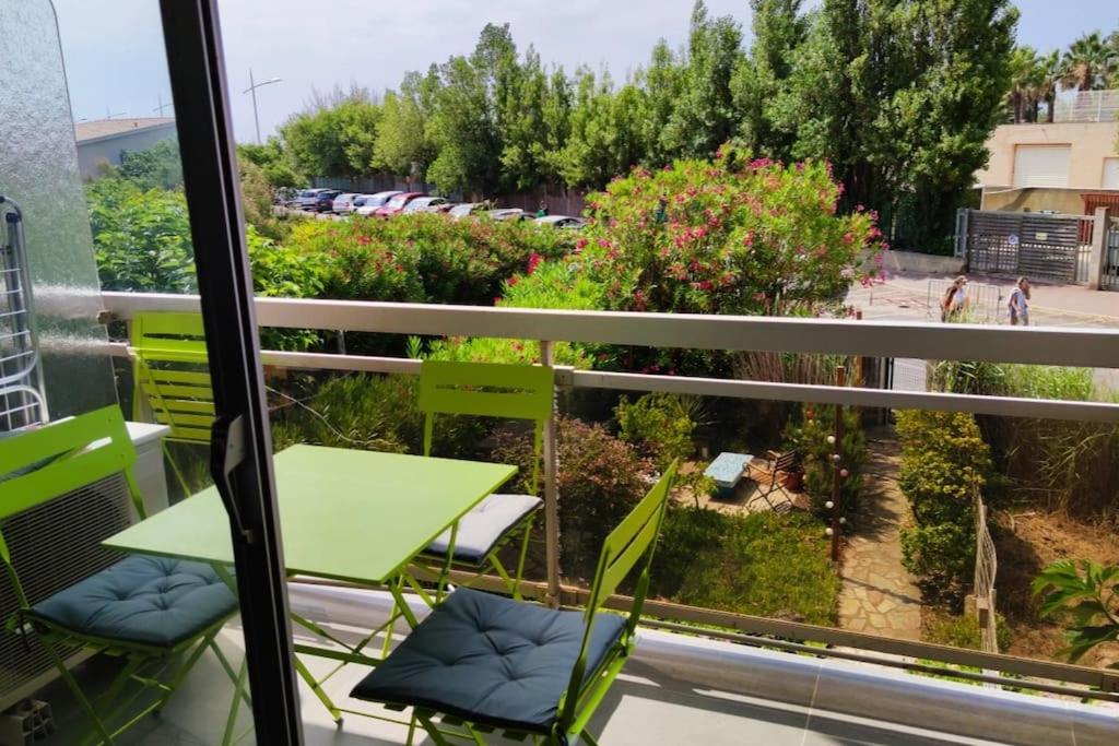una mesa verde y sillas en un balcón con vistas en Plages 130 m, parking privé, climatisé, wifi/fibre, en Valras-Plage