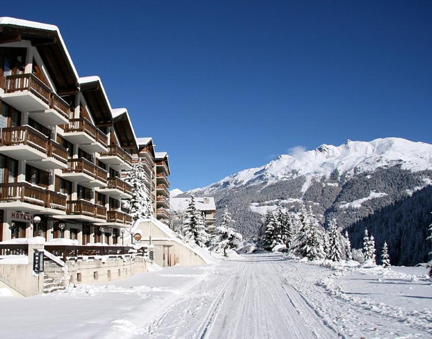 Une route enneigée se trouve en face d'un lodge de ski. dans l'établissement Hôtel Cristal - Swiss Riders Lodge Grimentz, à Grimentz