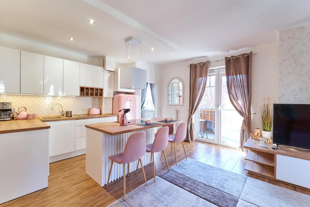 a kitchen with white cabinets and a bar with pink stools at LAGUNA Apartament 22 Willa Leśna in Polanica-Zdrój