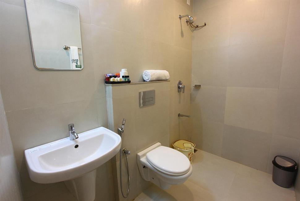een badkamer met een wastafel, een toilet en een spiegel bij zoz Idukki in Munnar