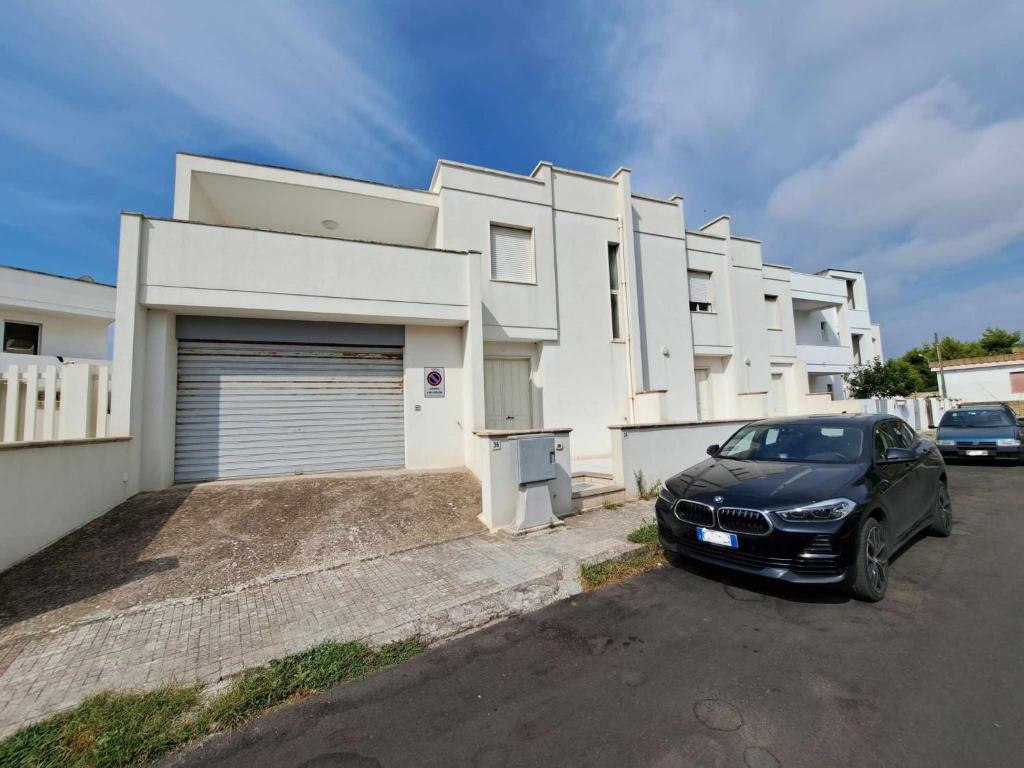 un coche negro estacionado frente a un edificio blanco en Villette smile s m di leuca, en Leuca