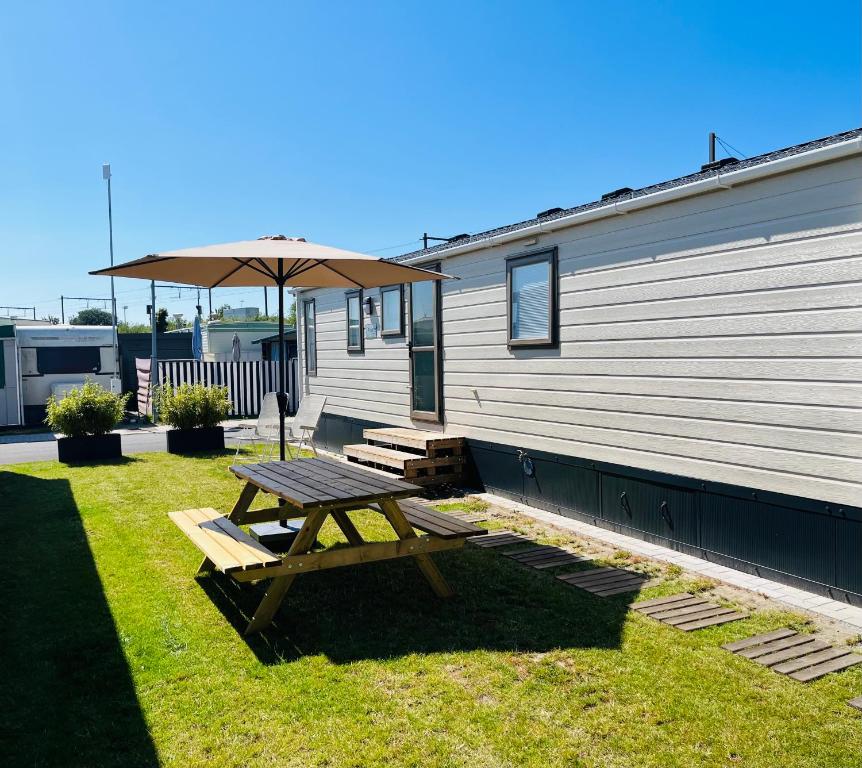 a picnic table with an umbrella next to a trailer at Luxury seaside cottage 29 in Knokke-Heist