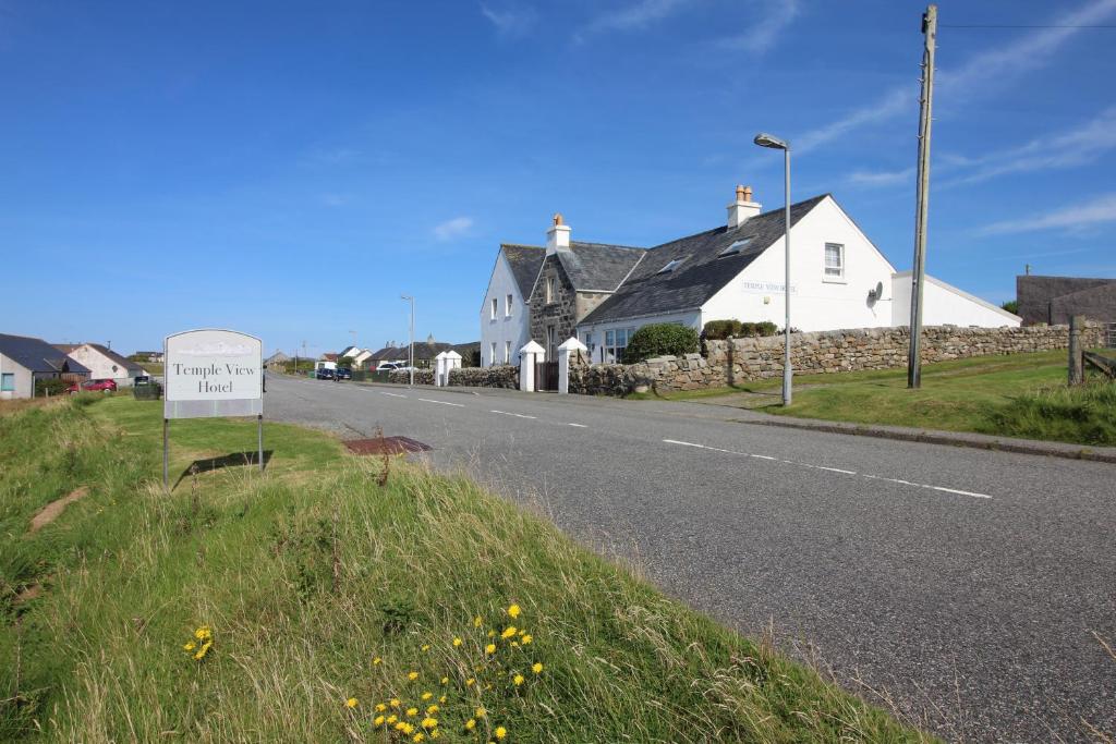 una casa con un letrero al lado de una carretera en Temple View Hotel, en Carinish