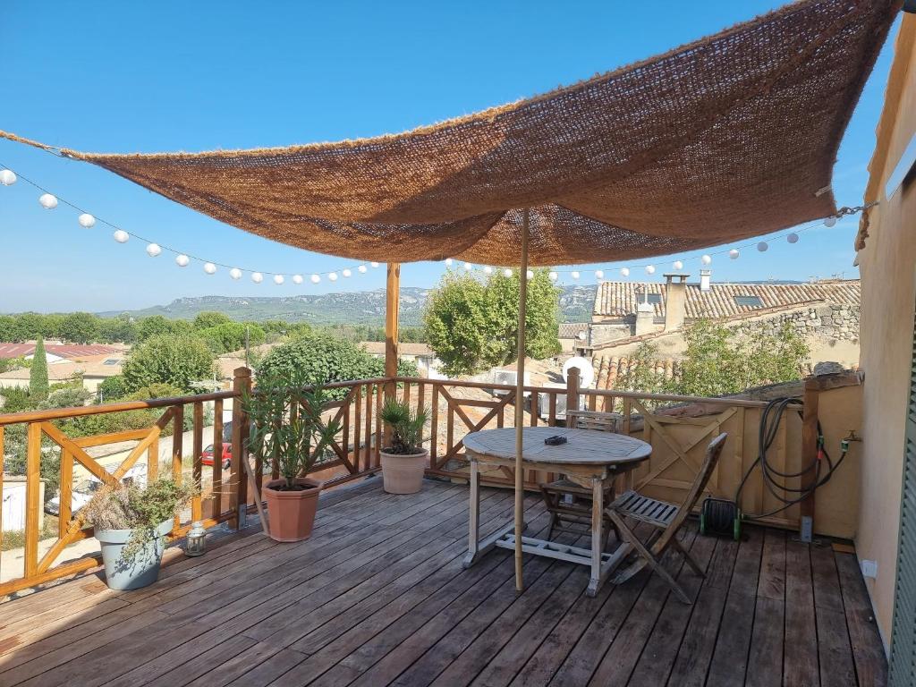 een houten terras met een tafel en een parasol bij Gîte Durance Mallemort in Mallemort
