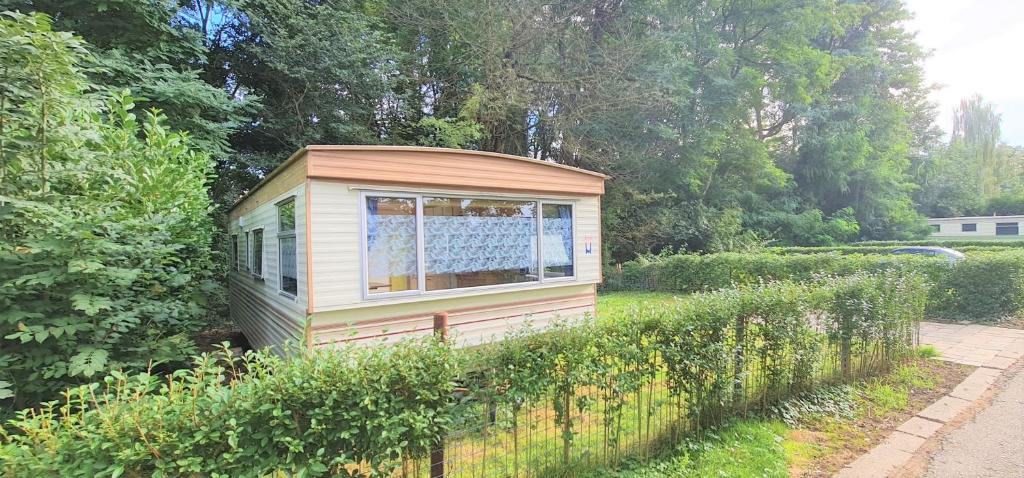 a small shed in a garden next to a fence at Stacaravan in de natuur bij Maastricht in Ulestraten
