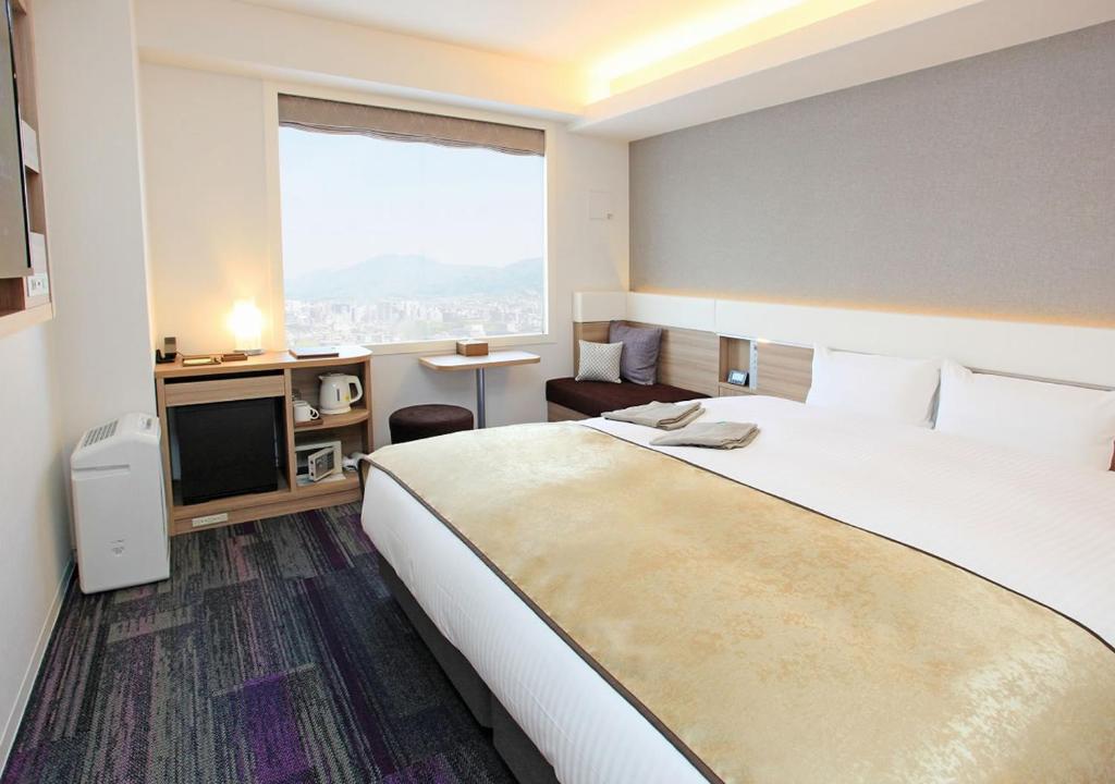a hotel room with a large bed and a television at Urban Hotel Kyoto Gojo Premium in Kyoto