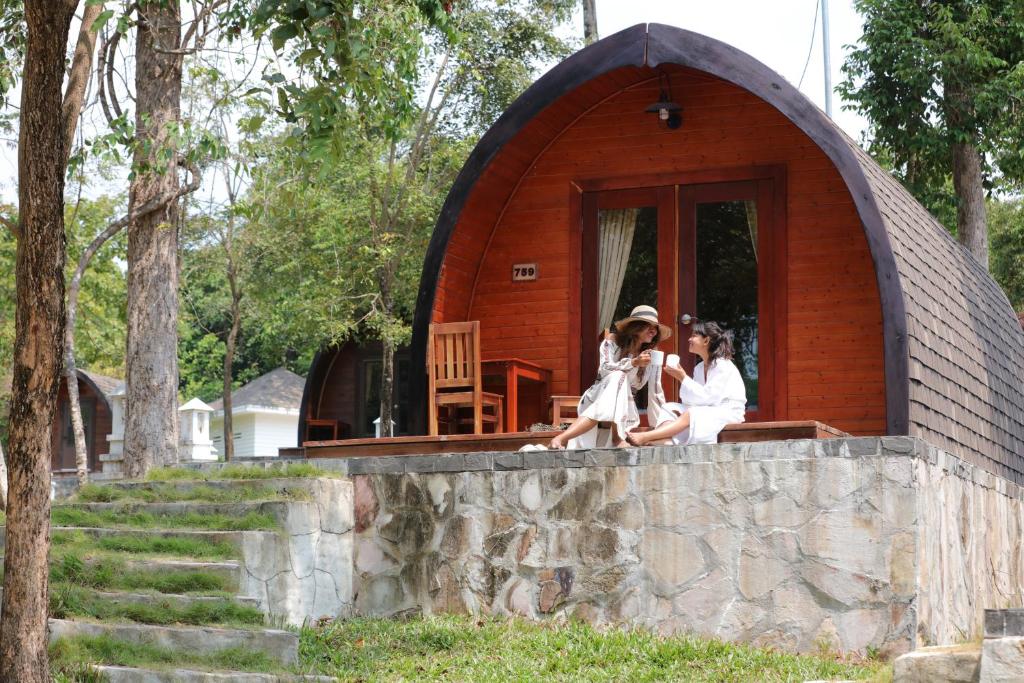 two women sitting on the porch of a tiny house at Pod Village by Independence Hotels in Sihanoukville