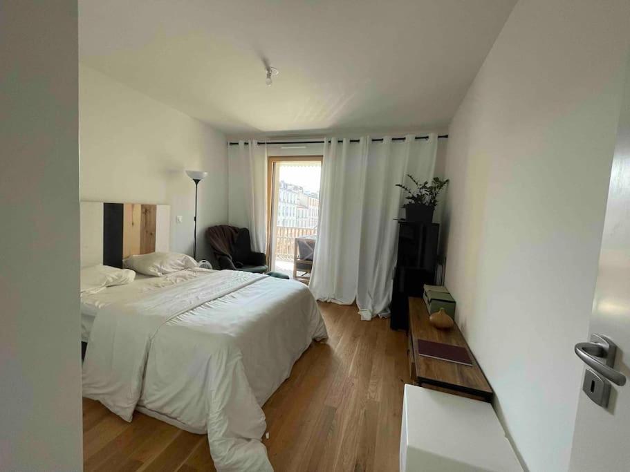 a bedroom with a white bed and a window at Magnifique logement avec terrasse &amp; climatisation in Aubervilliers