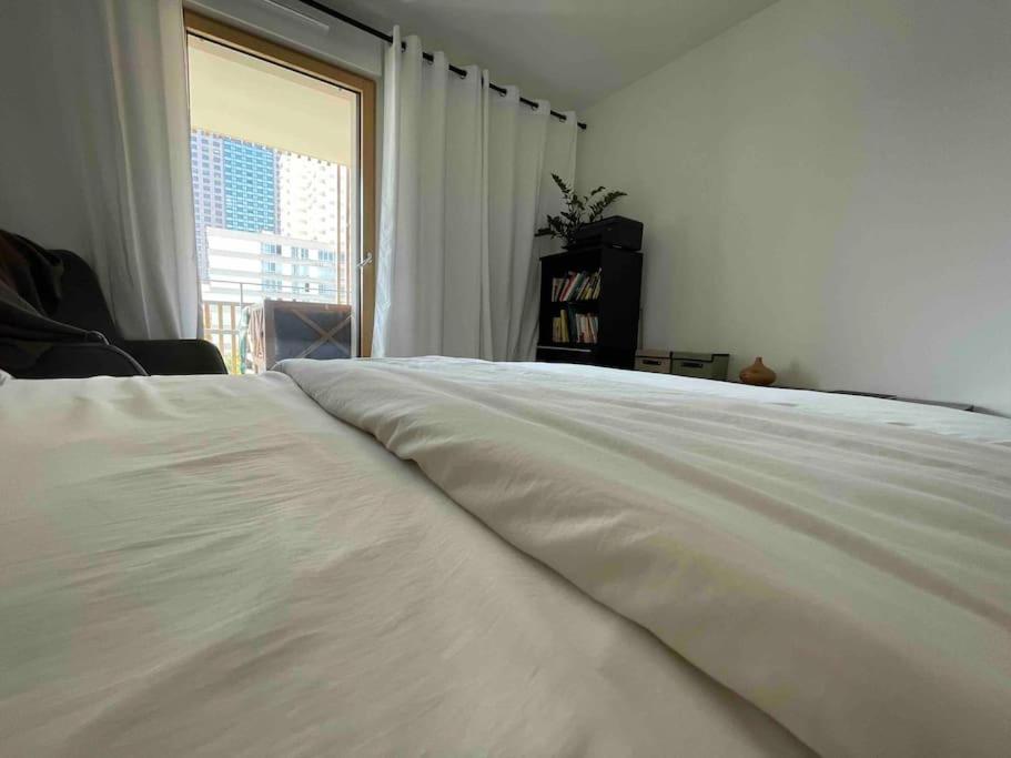 a large white bed in a room with a window at Magnifique logement avec terrasse &amp; climatisation in Aubervilliers