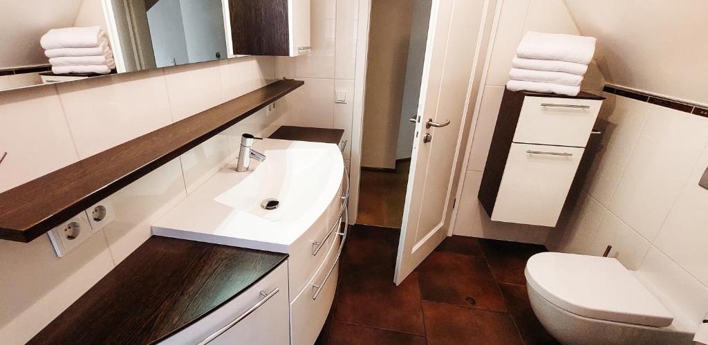 a white bathroom with a toilet and a sink at Ferienwohnungen am Tor in Langenburg