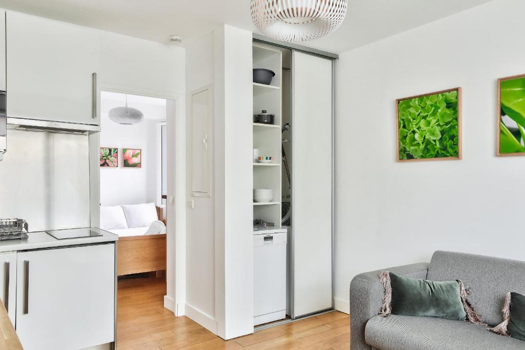 a white living room with a couch and a kitchen at Charmant appartement à 10 min de la Défense in Suresnes