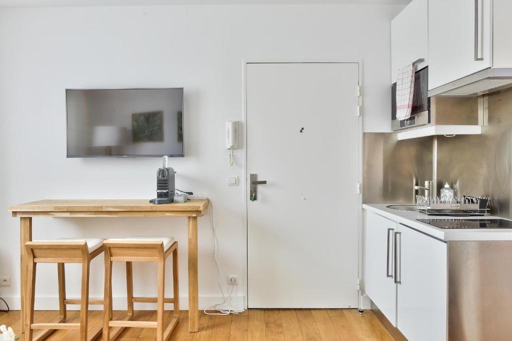 a kitchen with white cabinets and a table and chairs at Charmant appartement à 10 min de la Défense in Suresnes