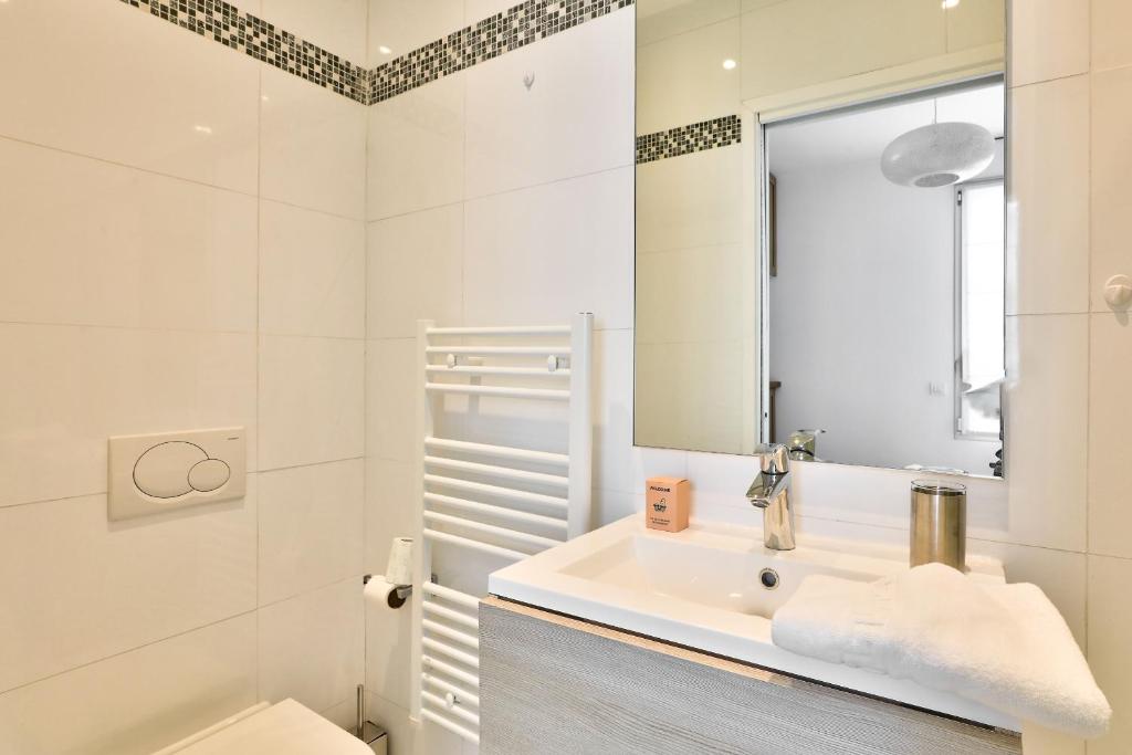a white bathroom with a sink and a mirror at Charmant appartement à 10 min de la Défense in Suresnes