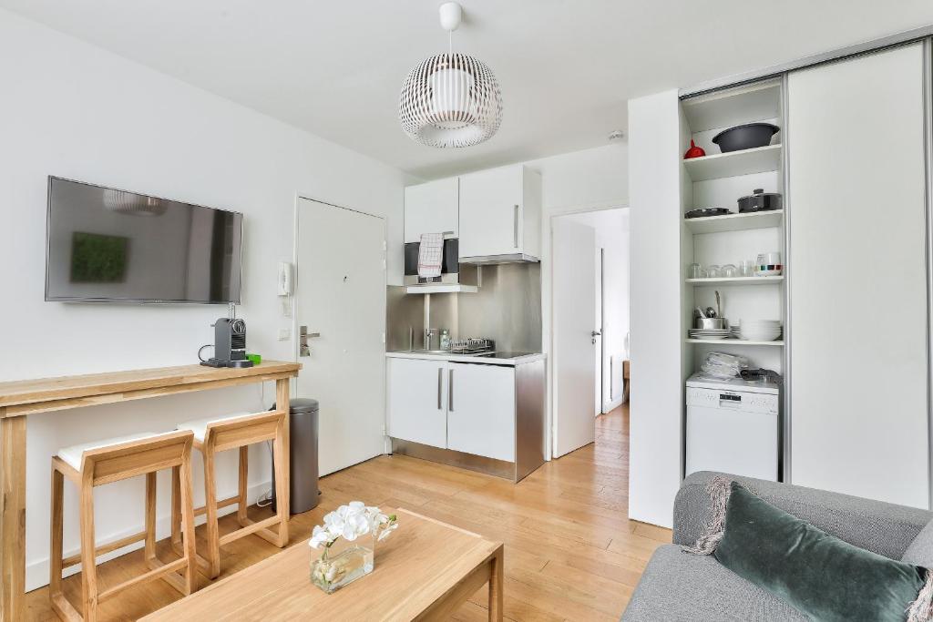 a kitchen and living room with white cabinets and a table at Charmant appartement à 10 min de la Défense in Suresnes