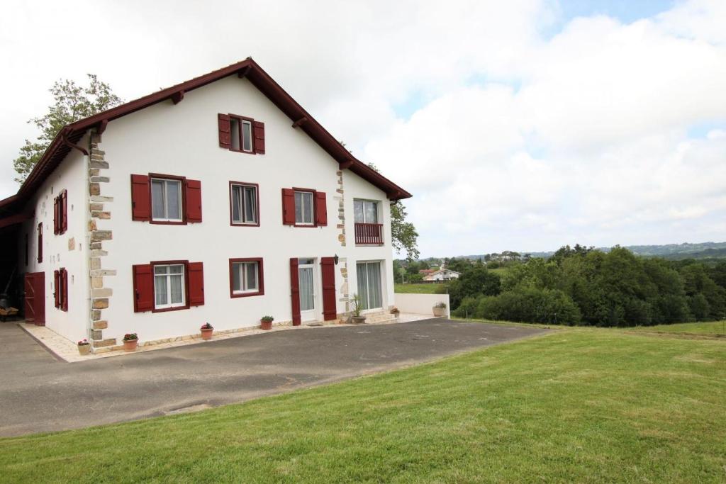 a large white house with red shuttered windows at Maliania in Arbonne