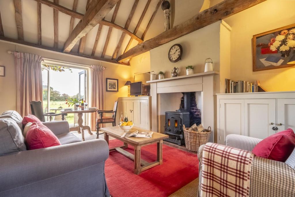 un salon avec des canapés et une cheminée dans l'établissement Acorn Cottage, à Blickling