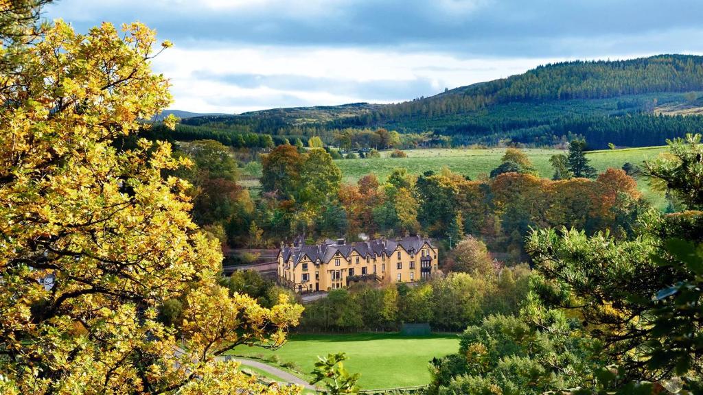 ein großes Haus inmitten eines Feldes mit Bäumen in der Unterkunft Craigellachie Hotel of Speyside in Craigellachie