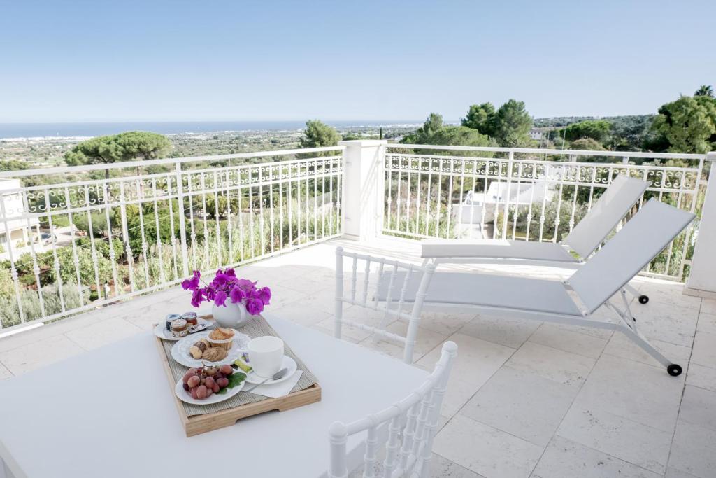 a white balcony with a table and chairs and a view at San Lorenzo Boutique Hotel & SPA in Polignano a Mare