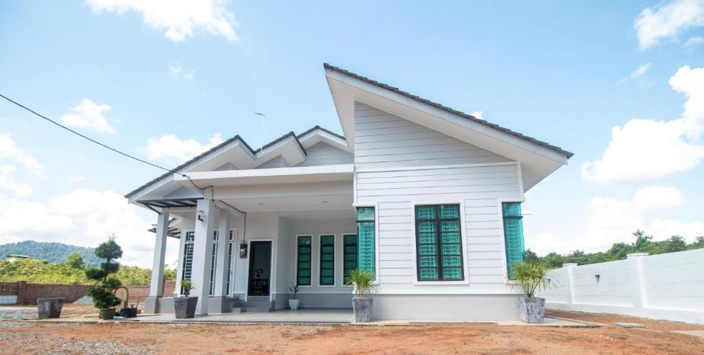 uma casa branca com janelas verdes fechadas em Romi Homestay Wakaf Tapai em Marang