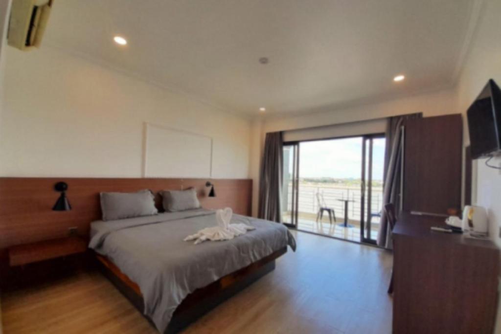 a bedroom with a bed and a large window at 4 RIVERS HOTEL in Phnom Penh