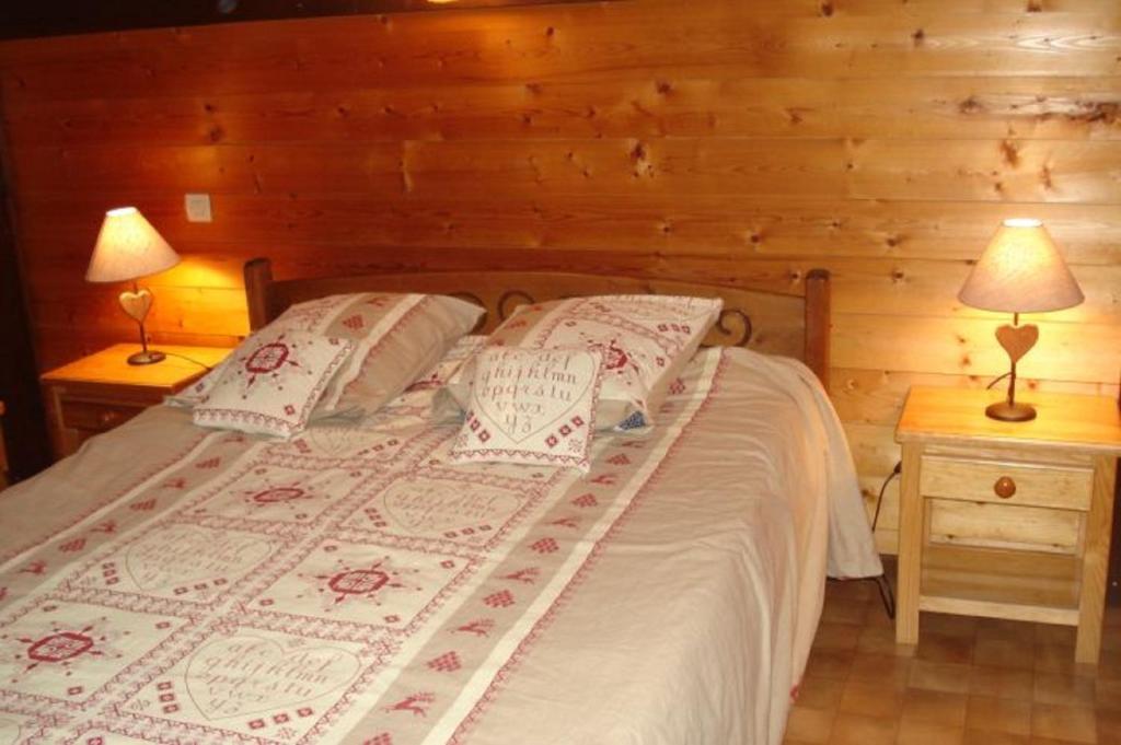 Cama en habitación de madera con 2 lámparas en Le Petit Paddock en Saint-Gervais-les-Bains