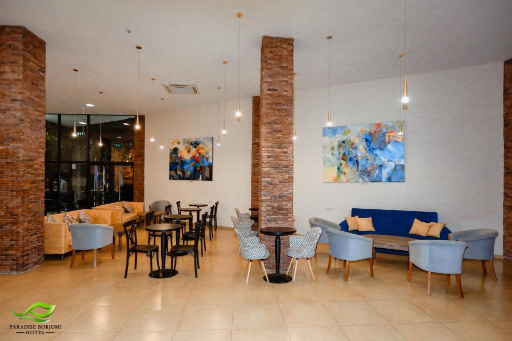 a restaurant with tables and chairs and a couch at Paradise Borjomi Hotel in Borjomi