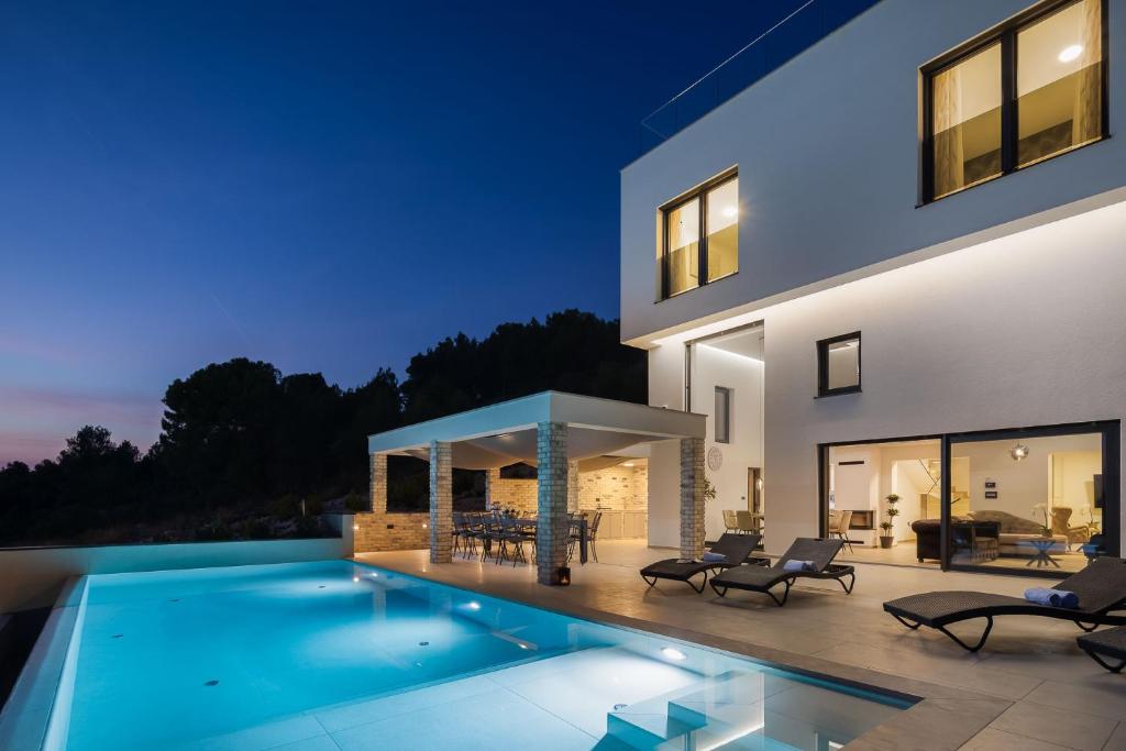 a house with a swimming pool at night at Villa GRC in Zaboric