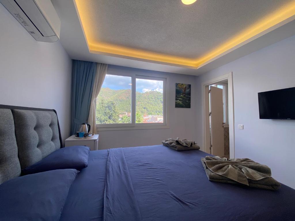 Schlafzimmer mit einem großen blauen Bett und einem Fenster in der Unterkunft Mert Homes Marmaris in Marmaris