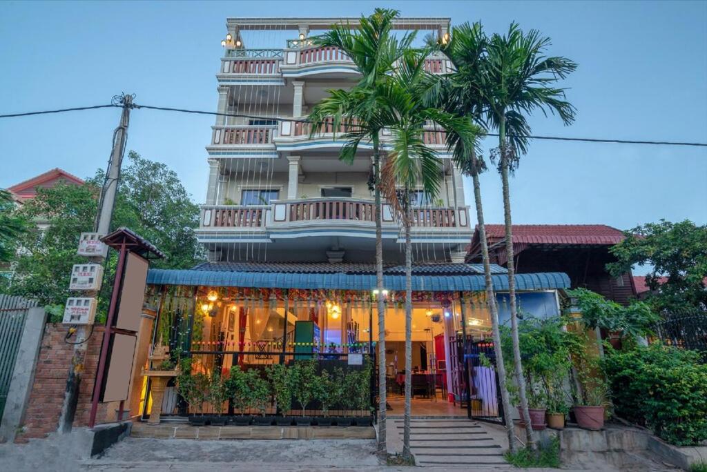 a building with palm trees in front of it at CENTRAL BACKPACKER in Siem Reap