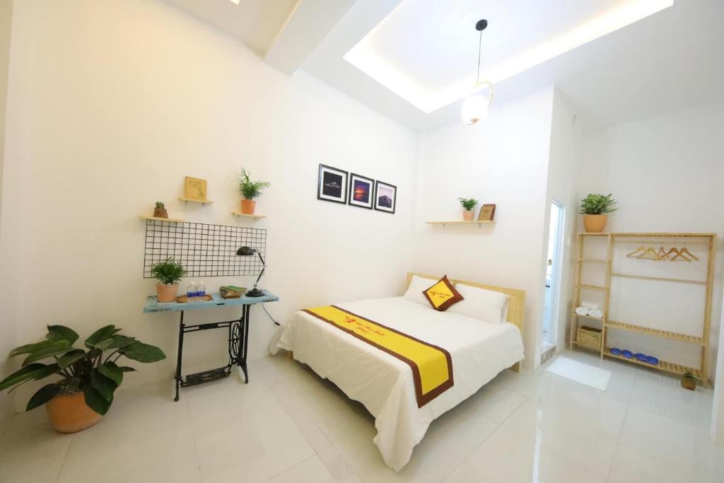 a white bedroom with a bed and a table at HOTEL VĂN THÁI BÌNH in Trà Vinh