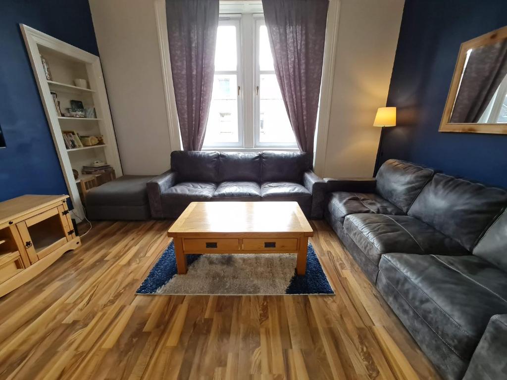 - un salon avec un canapé en cuir et une table basse dans l'établissement The Edinburgh Victorian - 3 Bedroom Apartment, à Édimbourg