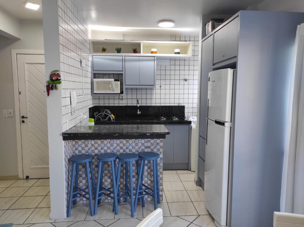 cocina con encimera con taburetes azules en APTO 50M PRAIA- 4 PESSOAS, WIFI, SACADA, CHURRASQUEIRA, GARAGEM PARA VEICULOS PEQUENOS - Residencial Roveda, en Bombinhas