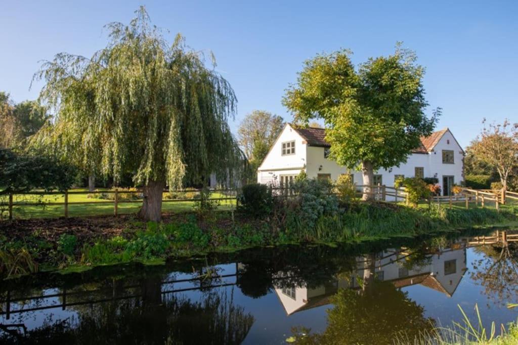 a house and trees next to a river at Peaceful Riverside Five Bed Cottage in Somerset in Langport
