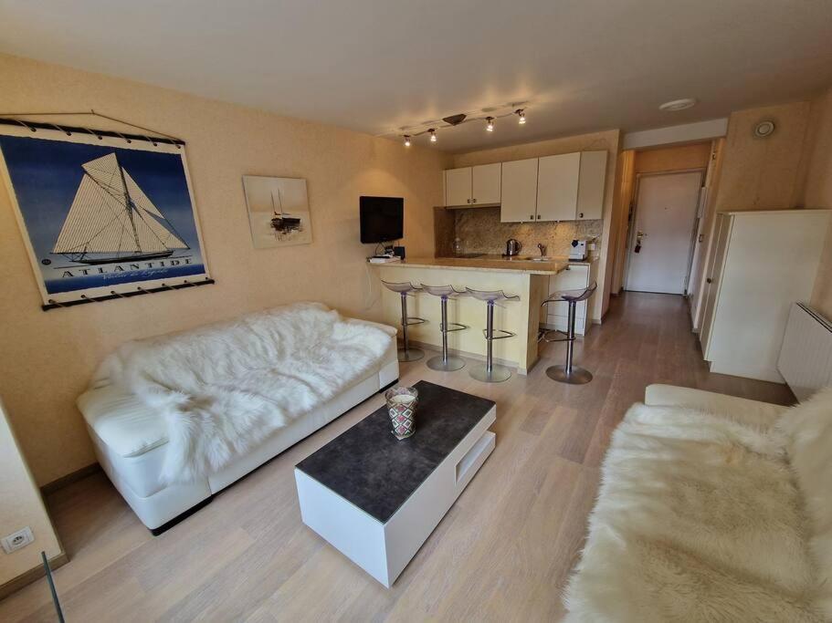 a living room with a white couch and a kitchen at Charmant studio Deauville, proche plage avec parking privé in Deauville