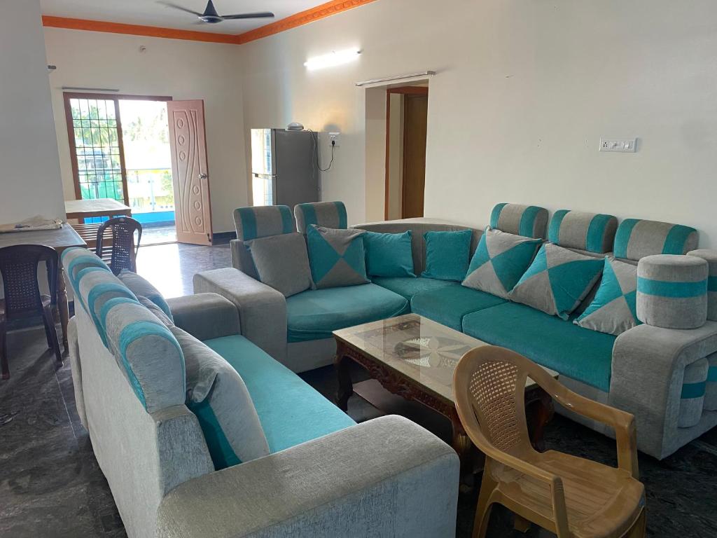 ein Wohnzimmer mit einem blauen Sofa und Stühlen in der Unterkunft NETHRA ILLAM in Chennai