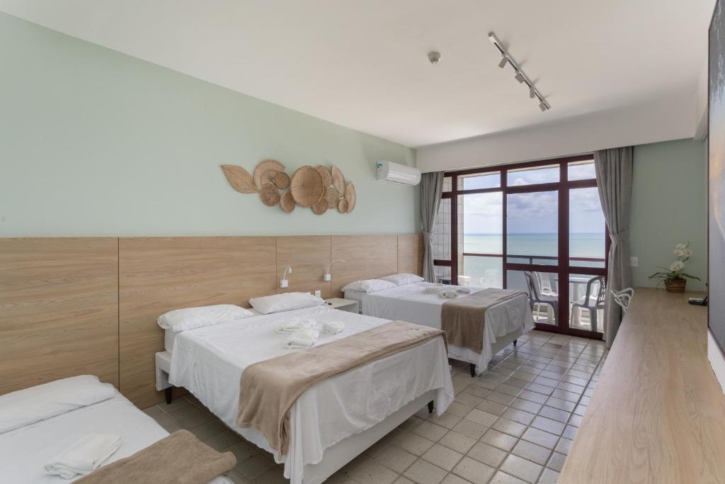 Habitación de hotel con 2 camas y balcón en Flat Edf Golden Beach, en Recife
