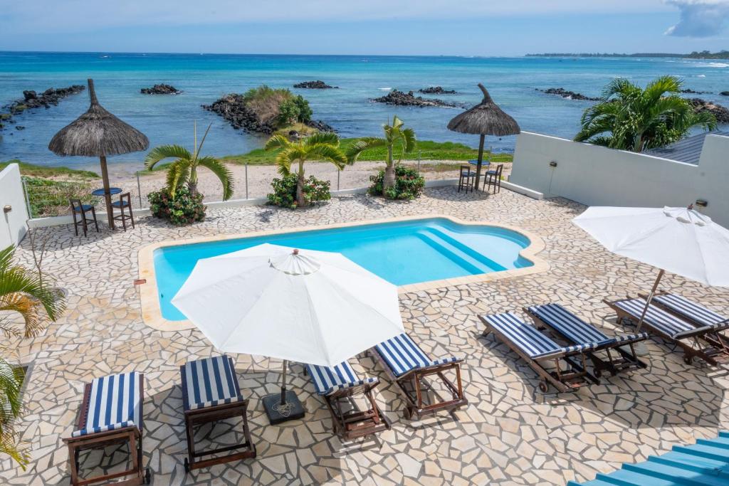 an image of a swimming pool with chairs and umbrellas at Beachfront Apartment - View to Die For in Triolet