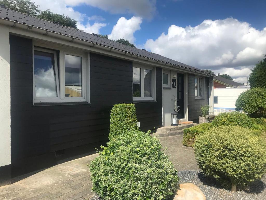 a black house with bushes in front of it at 170 M2 stort hus tæt på centrum, MCH og Boxen in Herning