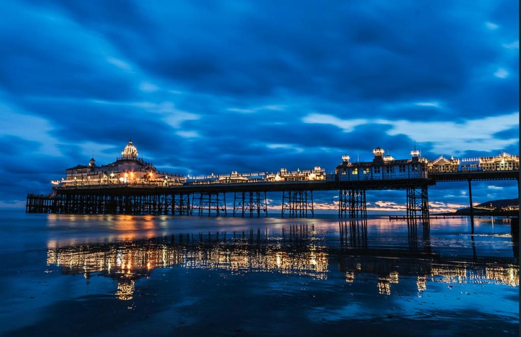 a pier at night with the reflection in the water at Premium Double-Ensuite Accommodation, Ideal for Relocators, contractors and Working Professionals, close to Eastbourne district general hospital in Eastbourne